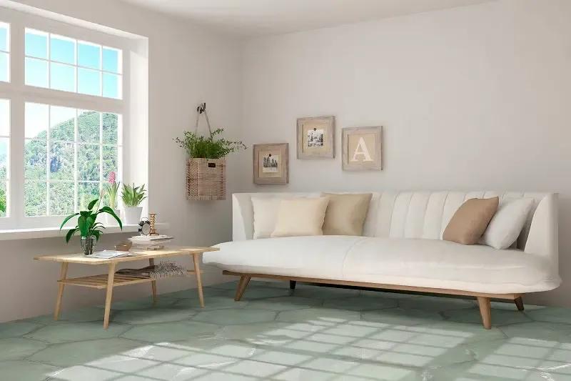 San Francisco A modern white daybed with light wood legs and three neutral throw pillows in a bright, minimalist living room with a green tiled floor.