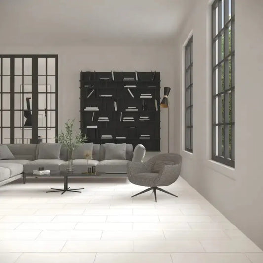 Bona De bianco 30x60 cm in A modern living room with a light gray sectional sofa, a gray swivel armchair, a black bookshelf, and large black-framed windows.