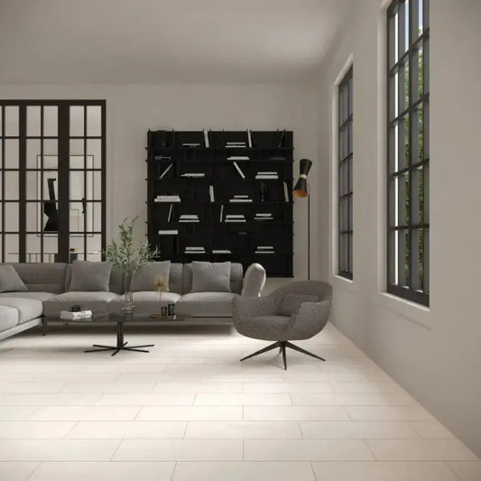 Bona De crema A modern living room interior with a gray sectional sofa, gray accent chair, black bookshelf, and large windows with black frames.